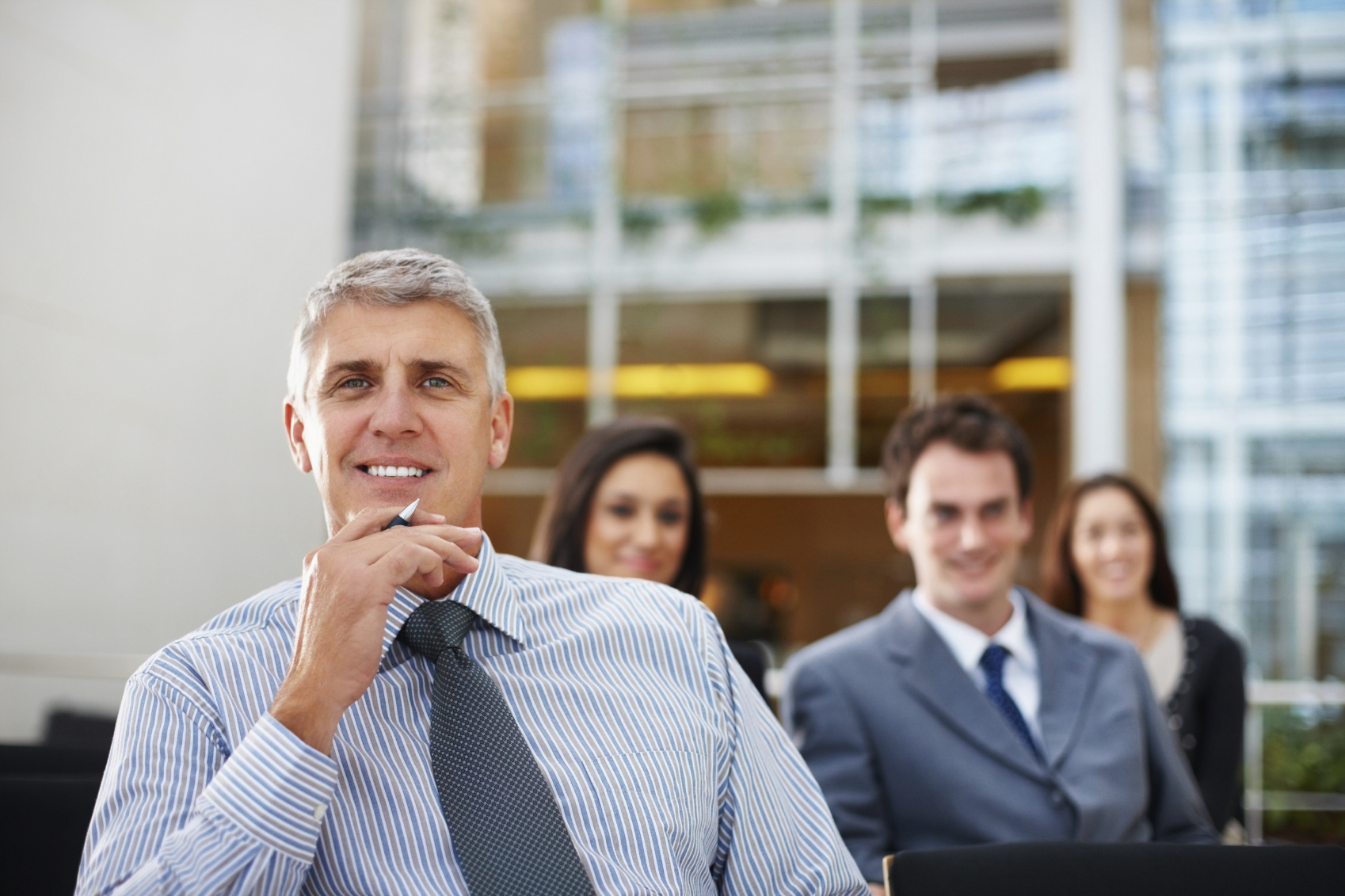 Mature business man attending presentation with team in blur background